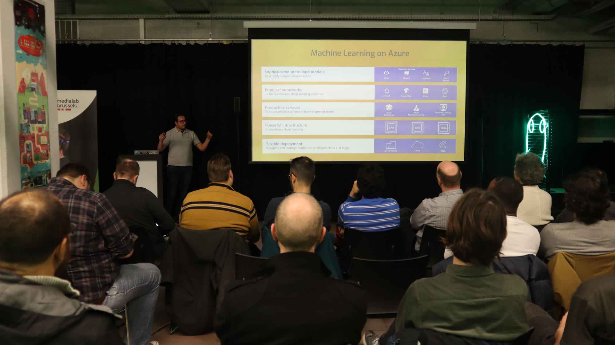 A small evening meetup room, about twenty-five developers in a few rows of chairs, all watching a slide about machine learning services