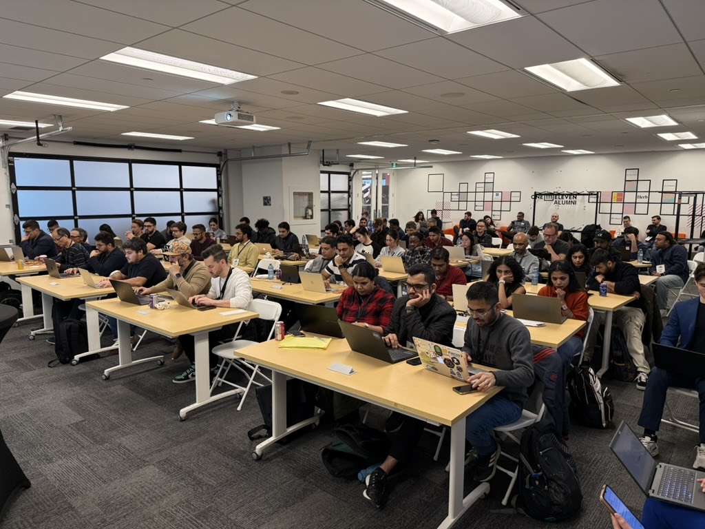 A room full of people at long tables, every one of them working on their own laptop during a hands-on session