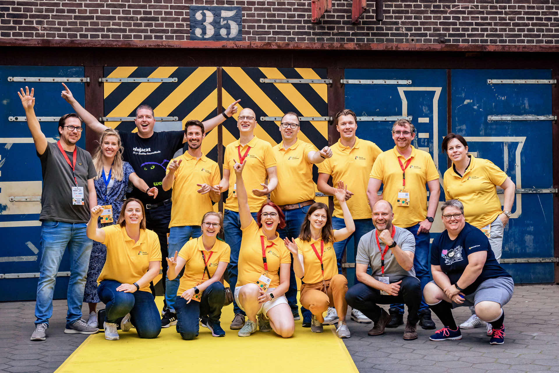 The Azure Lowlands organizing crew outside the venue, most of them in matching yellow volunteer shirts, laughing and posing for a group photo