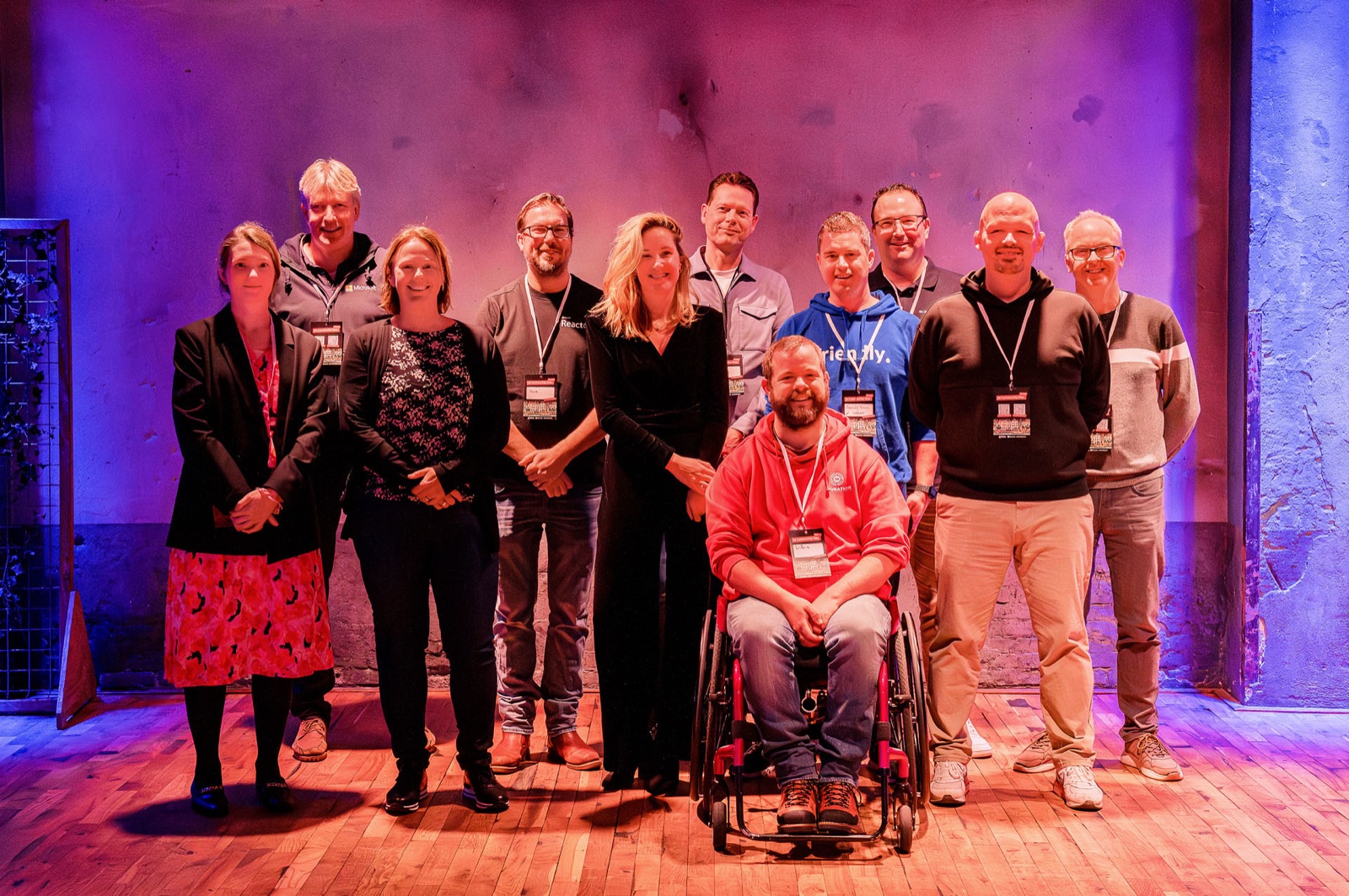 Group photo at AI Community Day Utrecht on a stage lit in purple and red